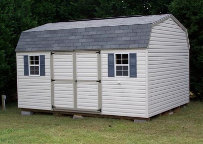 A vinyl shed sized 10x14. The roof is barn style and is shingled. Shed has a set of double doors and two windows with shutters