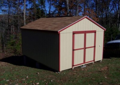 A 12x16, painted shed with a shingled a-roof style roof. Shed has red trim and no windows. Shed has a set of double doors