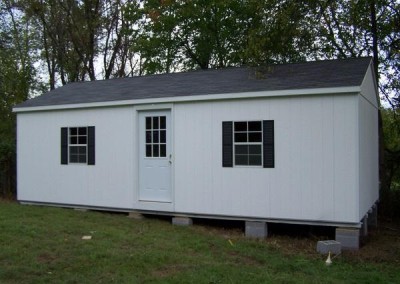 A 14x28 sized painted shed with an A-roof style, shingled roof. Shed has a house door with a window and two windows with shutters