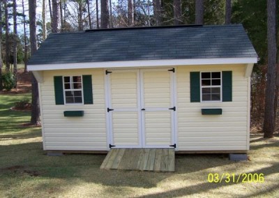 10X16 V-Carriage shed with green shutters and flower boxes. Shed has a double door and two windows with a wooden ramp